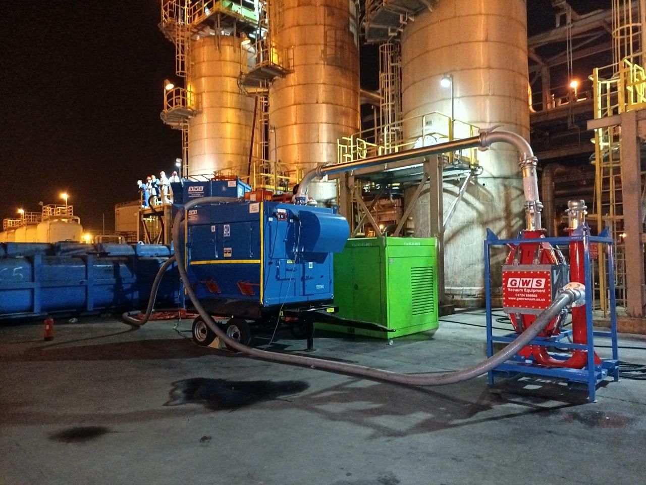 Subul Energy team operating a full catalyst handling vacuum system in front of refinery columns at night
